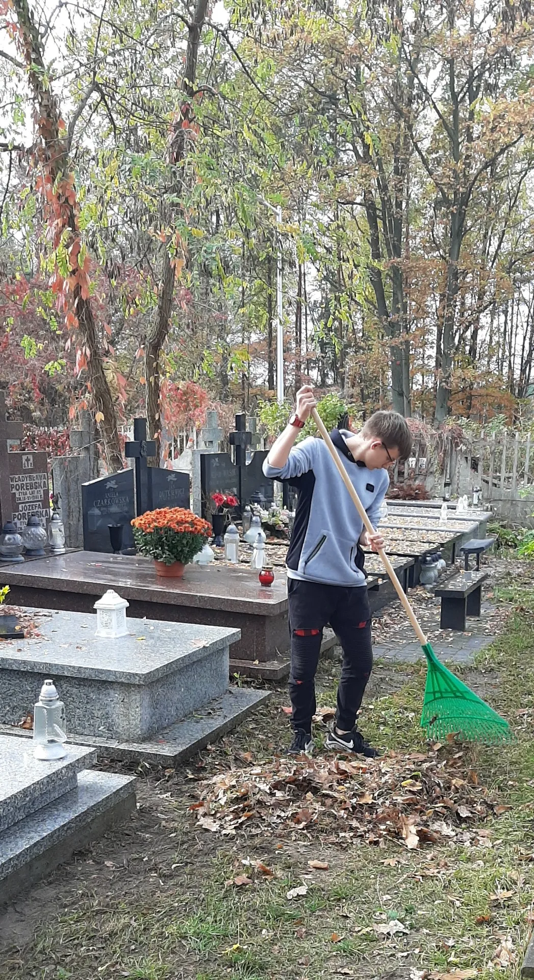 Uczniowie sprzątający cmentarz i groby