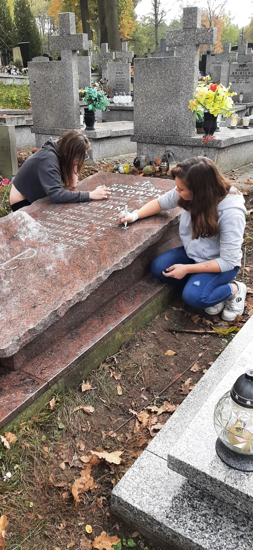 Uczniowie sprzątający cmentarz i groby