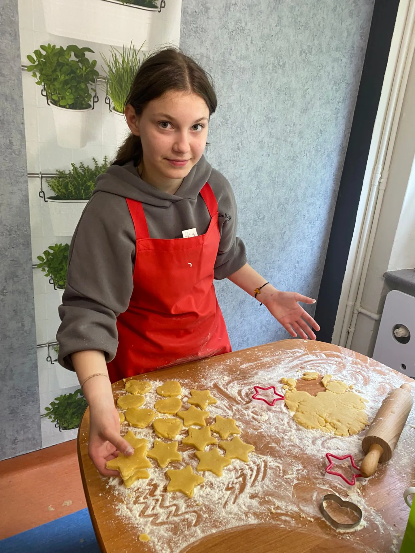 dziewczynka w czerwonym fartuchu pokazuje ciasteczka